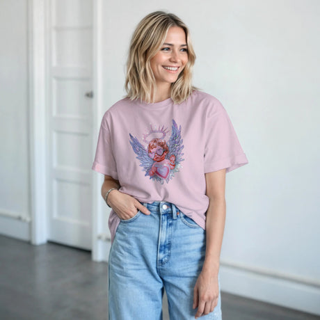 A woman wearing a pink t-shirt with an angel design and light blue jeans indoors.