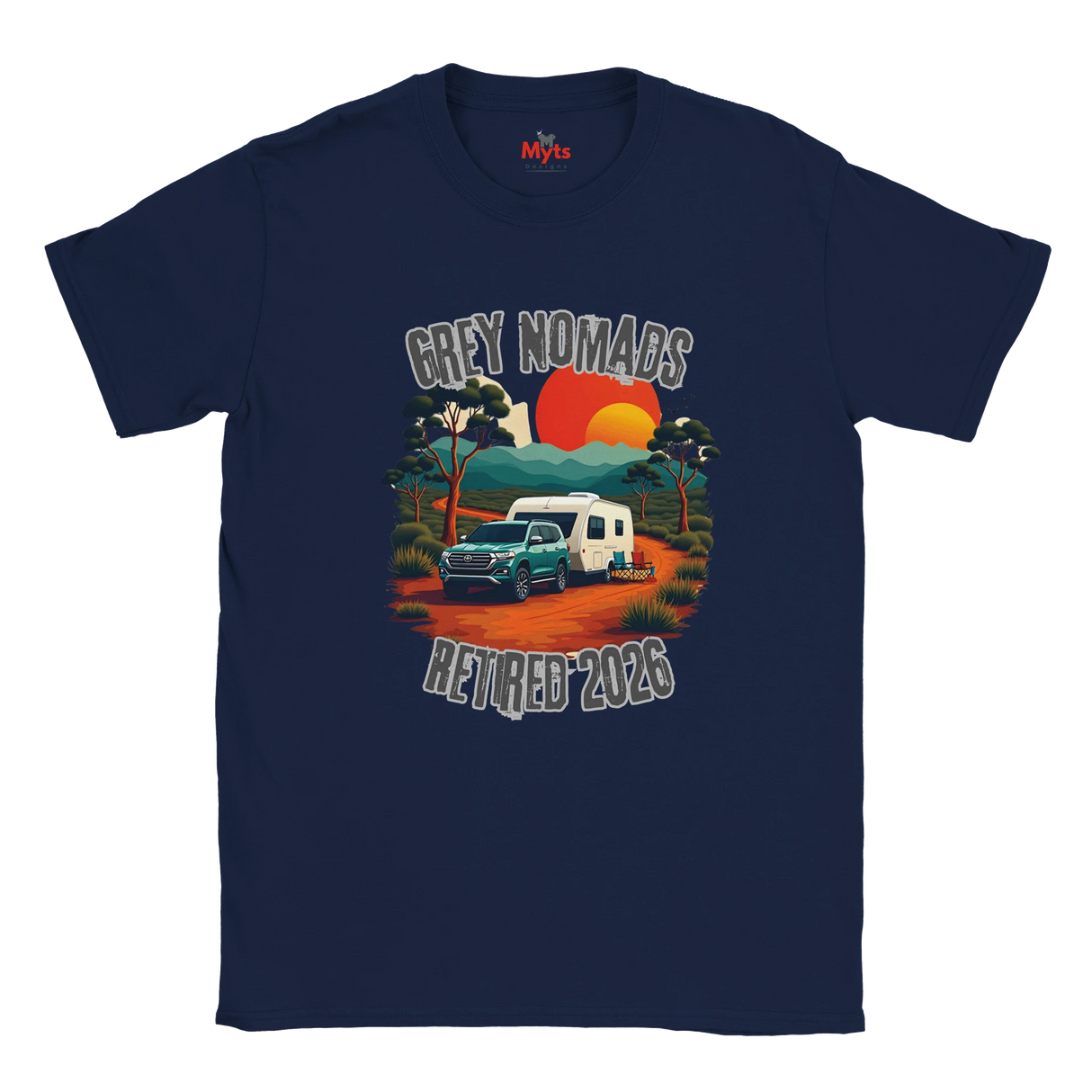 A navy blue short-sleeve t-shirt with a retro-style graphic on the front. The graphic features a teal pickup truck towing a white caravan on an orange dirt road, with a sunset in orange and yellow, trees, and the text 'GREY NOMADS RETIRED 2026'.