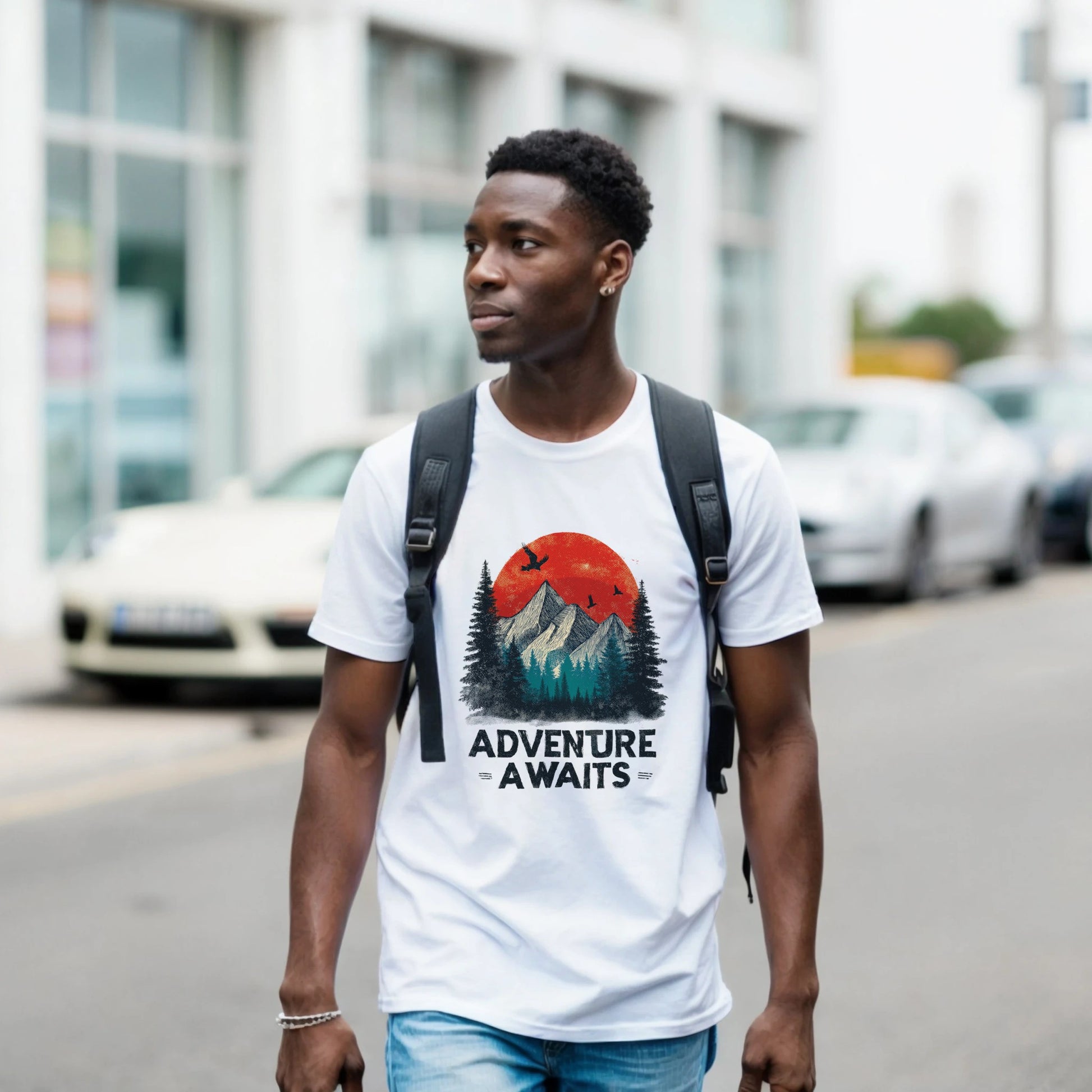 A man wearing a white t-shirt with the 'Adventure Awaits' graphic is walking on a street.