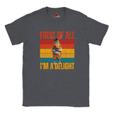 Casual dark heather tee displaying a retro-style donkey illustration with bold “First of All, I’m a Delight” vintage text, on a white background