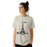Front view of a Sand coloued soft casual tee featuring a whimsical graphic of the Eiffel Tower with a retro‑style spaceship orbiting it, worn by a young woman.