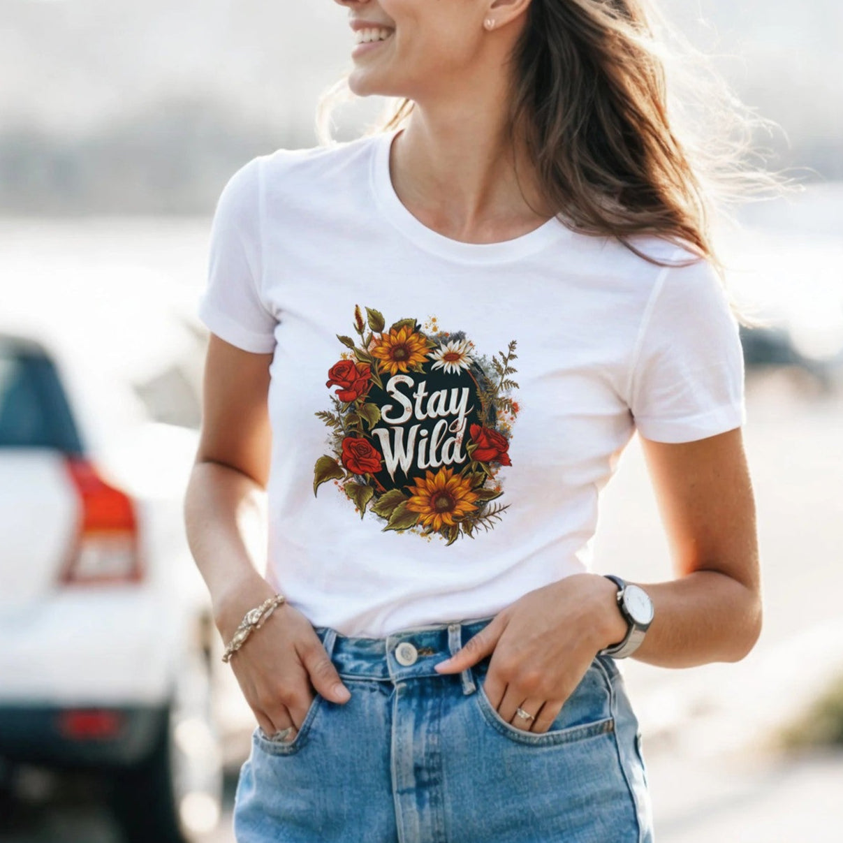 A woman wearing a white t-shirt with a floral design and text, standing outdoors.