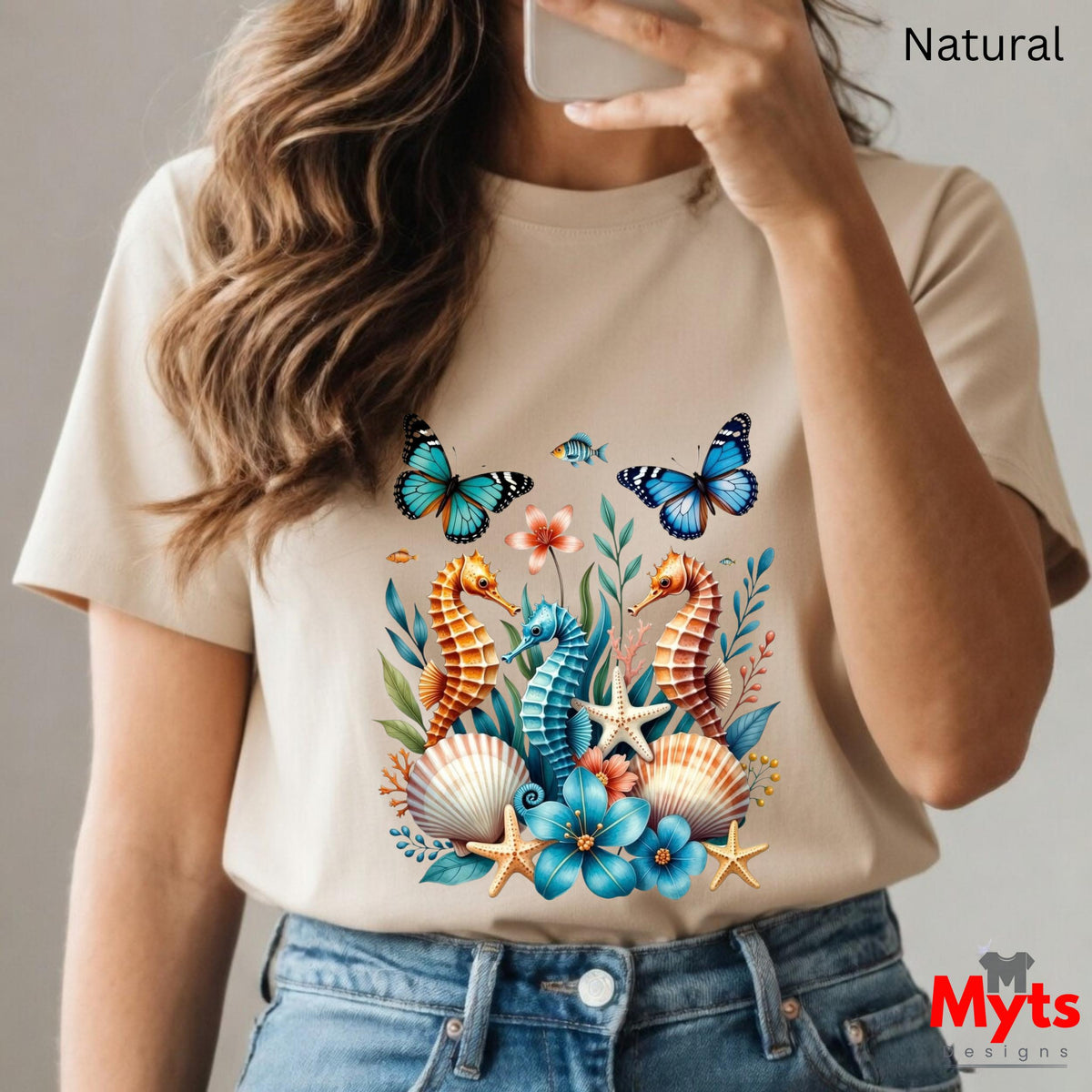 A natural graphic T-shirt featuring three colourful seahorses, blue butterflies, tropical flowers, starfish and seashells in a vibrant ocean wildlife design.