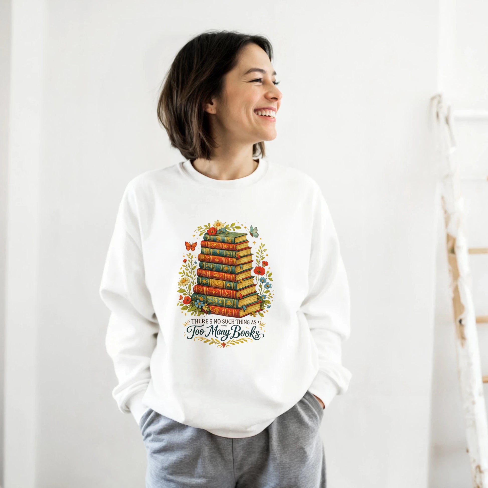 Person wearing a white sweatshirt with a colorful book-themed design on a plain background