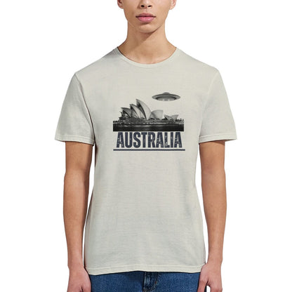 Front view of a young woman wearing a sand colored soft casual tee showing the Sydney Opera House sails with a sleek spaceship graphic orbiting overhead, printed on ultra-soft Gildan 64000 cotton