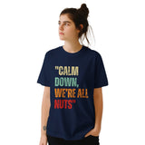 girl wearing A navy retro styled t-shirt, featuring distressed lettering "Calm Down, We're All Nuts" on a white background