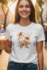 A woman holding a drink on a city street with a floral design on her shirt