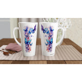 Two tall white ceramic mugs with butterfly and floral watercolor designs in blue, purple, and pink, displayed on a checkered placemat on a wooden table.