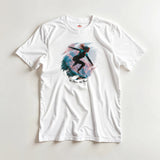White T-shirt with a graphic design of a girl surfing on a colorful background, displayed on a light gray surface.