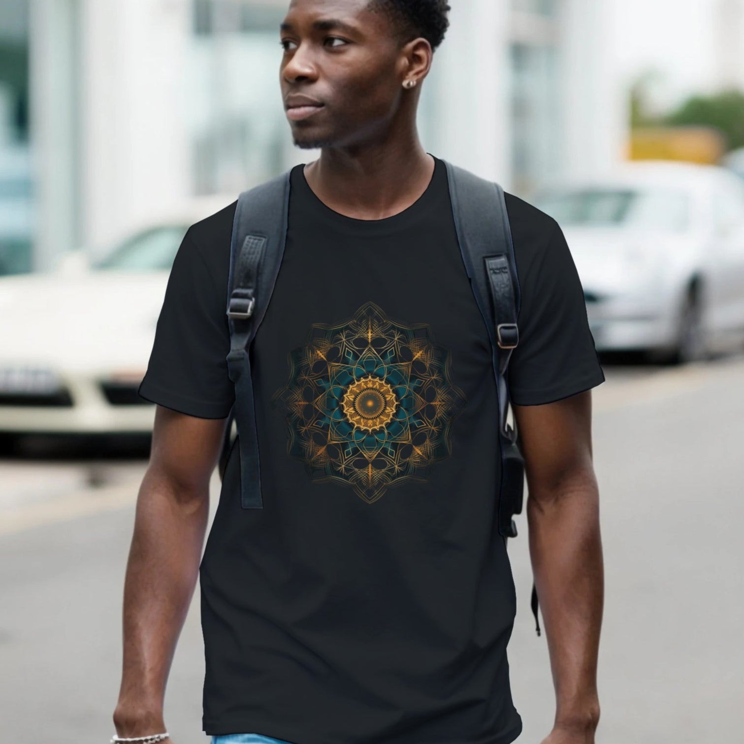 Man wearing a black t-shirt with a geometric design walking on a street.