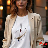 A woman wearing a white crewneck t-shirt with a minimalist abstract graphic print, styled with a beige blazer. The background is a softly blurred urban street scene with warm bokeh lights.