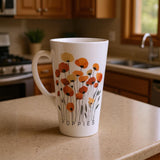 A white ceramic mug with a colorful poppy floral design and the word 'POPPIES' printed on the front, sitting on a beige kitchen countertop with a blurred kitchen background.