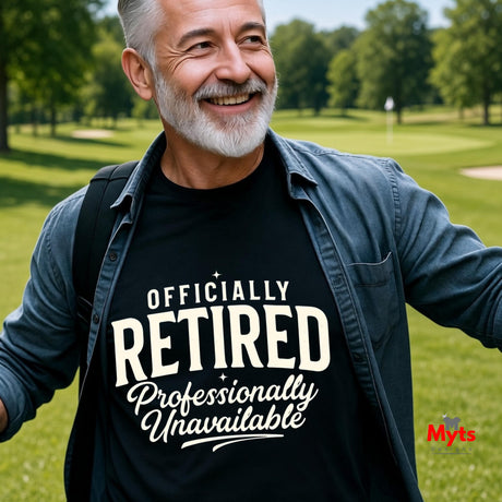 A smiling older man outdoors on a golf course wearing a black graphic T-shirt with white text that reads 'OFFICIALLY RETIRED Professionally Unavailable.' The shirt is layered under a dark blue button-up shirt, and a small 'Myts' mark appears in the lower right corner.