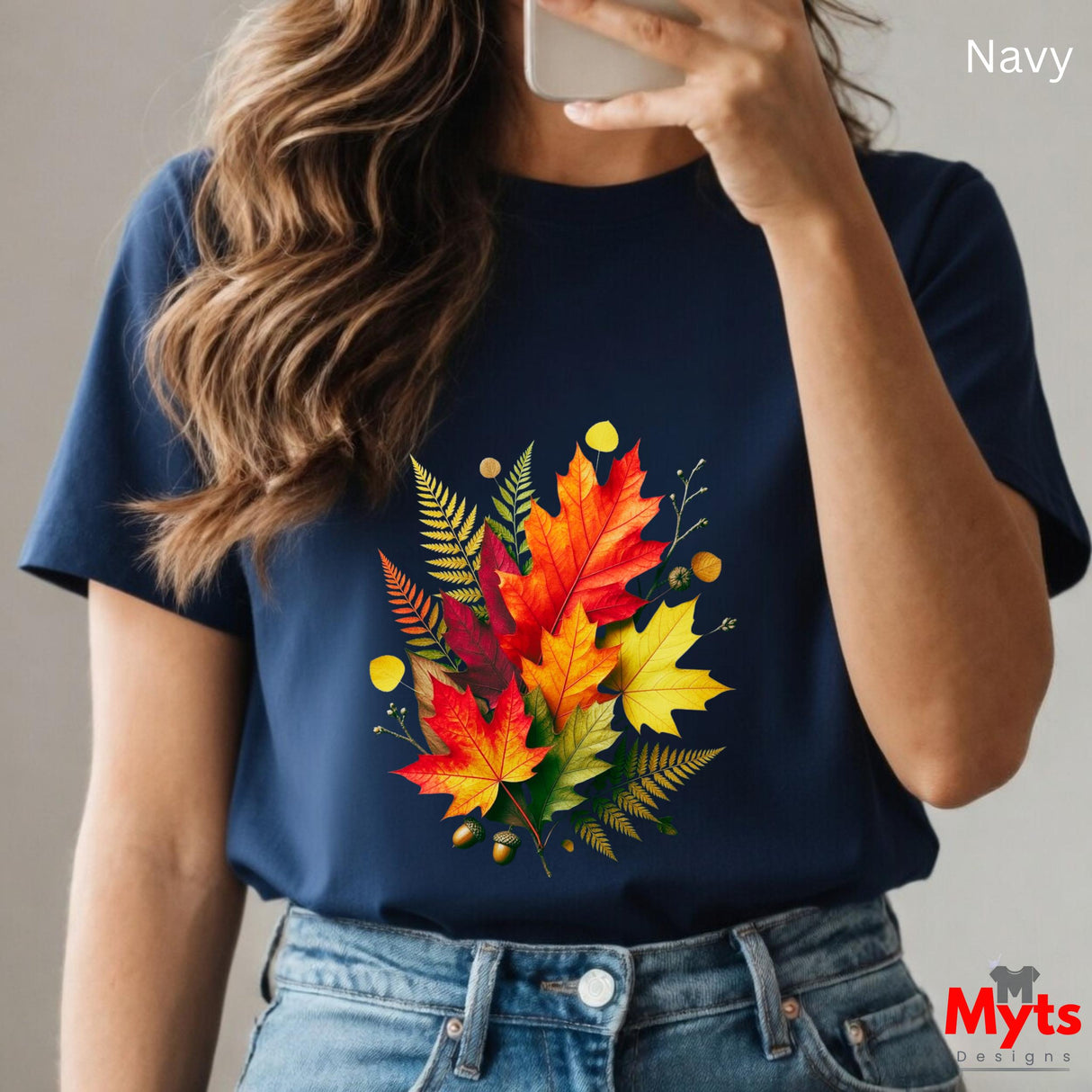 Person wearing a navy t-shirt with colorful leaf design, holding a phone.