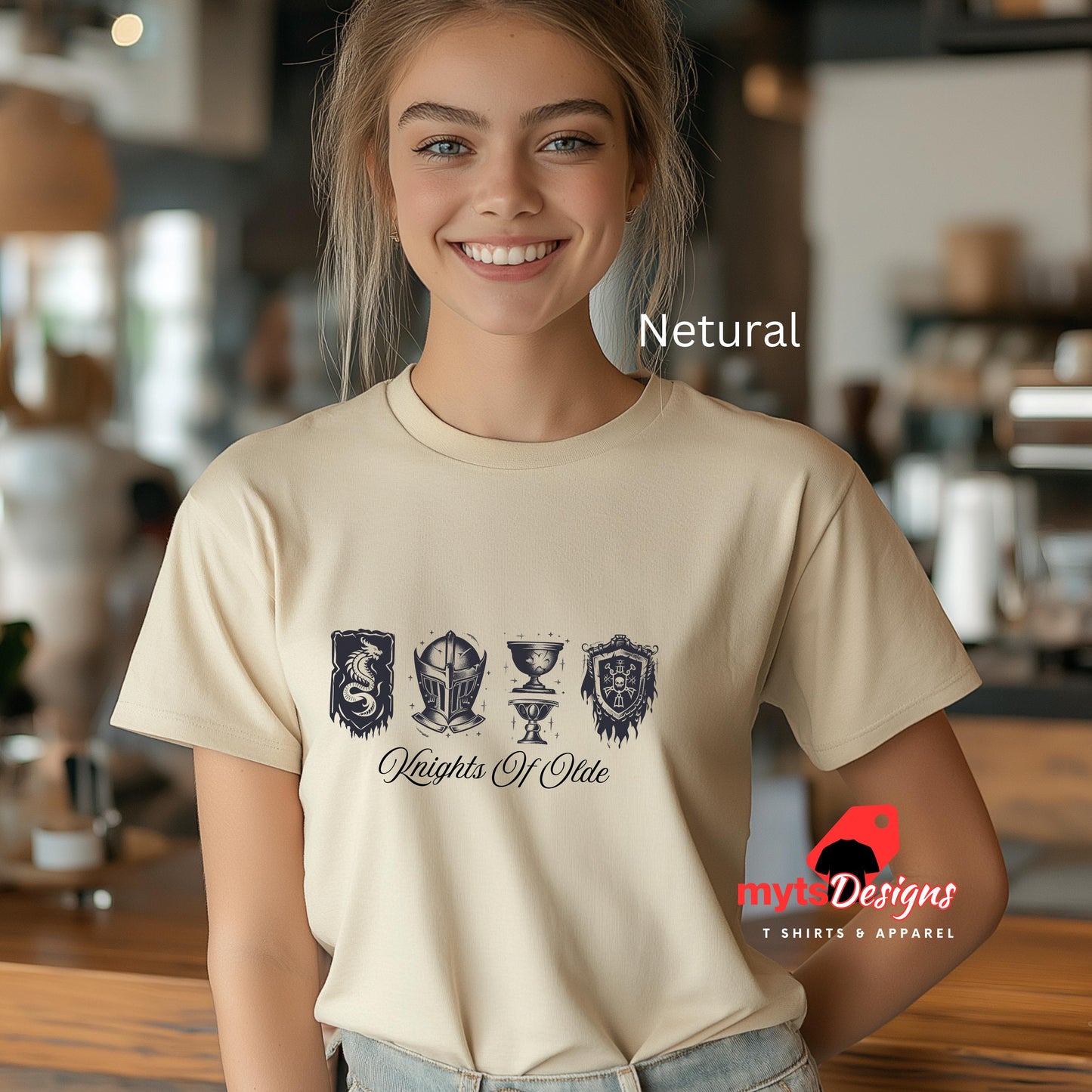 Woman wearing a beige t-shirt with 'Knights of Olde' design in a casual setting, with 'mytadesigns' logo.