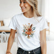 A woman wearing a white t-shirt with a floral design in a bright room.