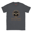 A dark heather gray crewneck t-shirt featuring a graphic of a raccoon inside a gold circle with the text 'R RACCOON Clever - Bold - Adaptable' printed below it.