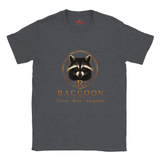 A dark heather gray crewneck t-shirt featuring a graphic of a raccoon inside a gold circle with the text 'R RACCOON Clever - Bold - Adaptable' printed below it.