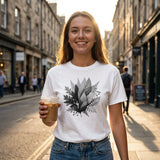 Woman wearing a white t-shirt with a leaf design, holding a coffee cup on a city street.