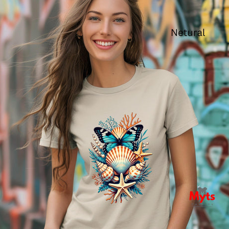 A woman is wearing a light Natural t-shirt with a colorful graphic of a butterfly, seashells, and starfish. The background is a blurred graffiti wall, and the text 'Natural' is visible in the top right.