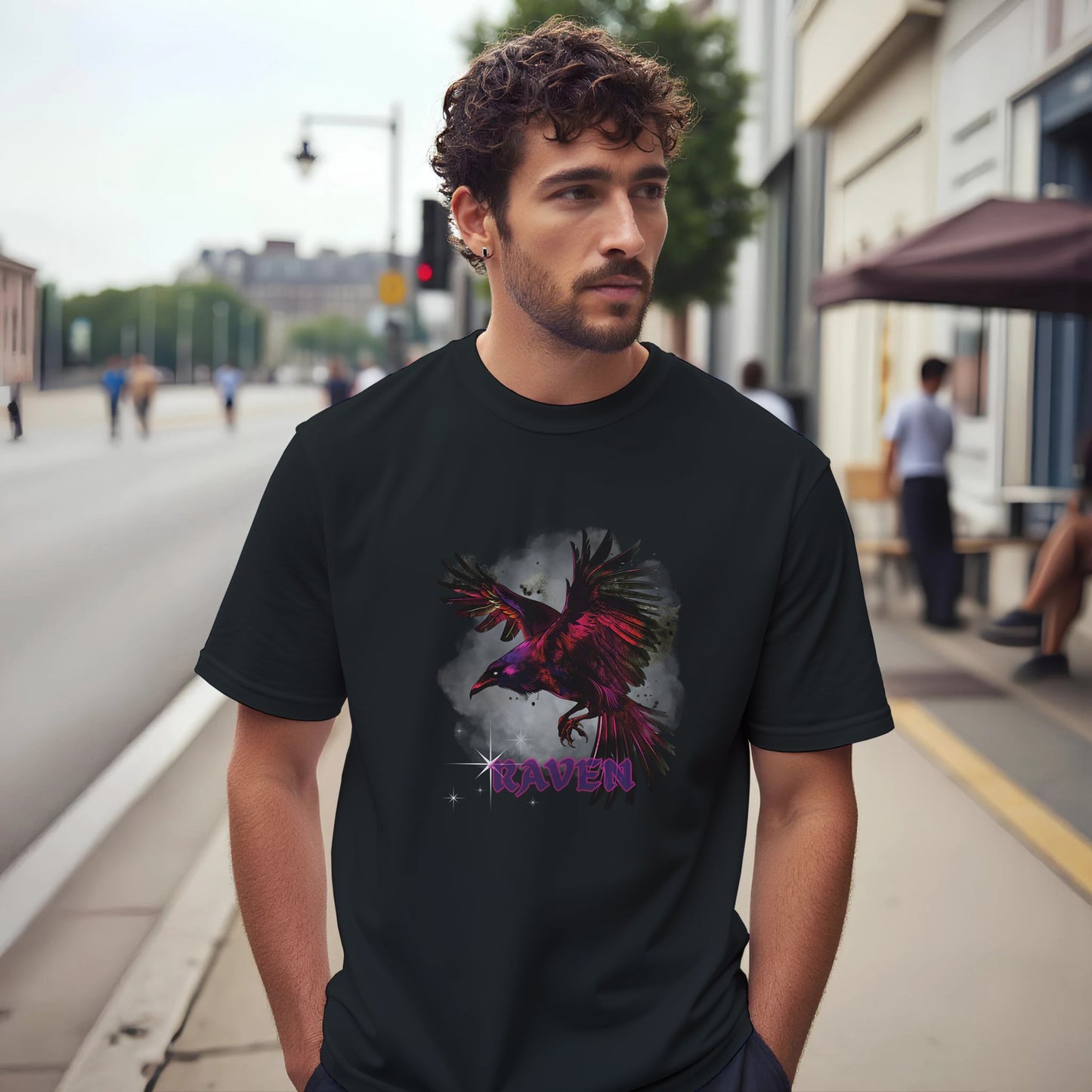A Man wearing a black t-shirt with a colorful raven design on a city street.