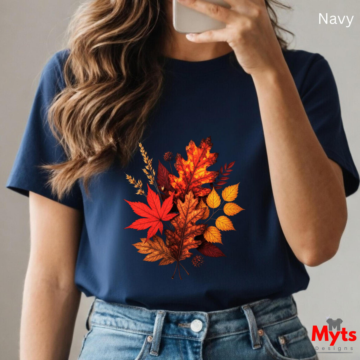 Person wearing a navy t-shirt with autumn leaf design, holding a phone.