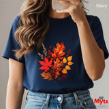 Person wearing a navy t-shirt with autumn leaf design, holding a phone.