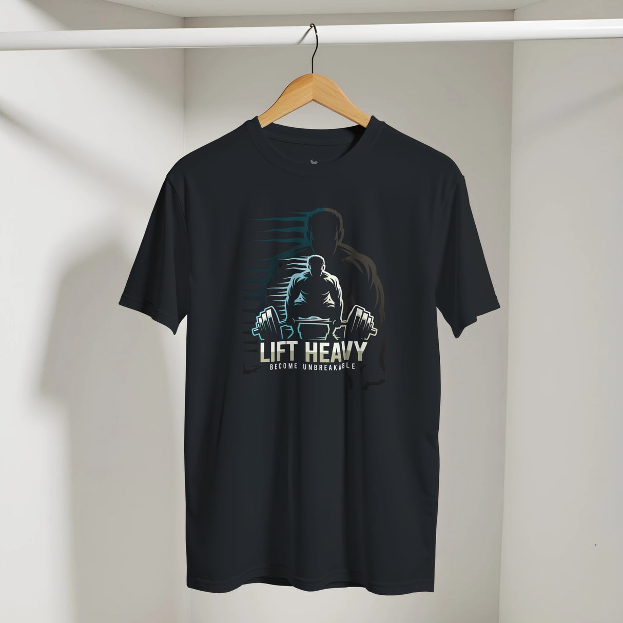 Black t-shirt with a graphic design of a person lifting weights and text 'Lift Heavy Become Unbreakable' on a hanger against a white wall.