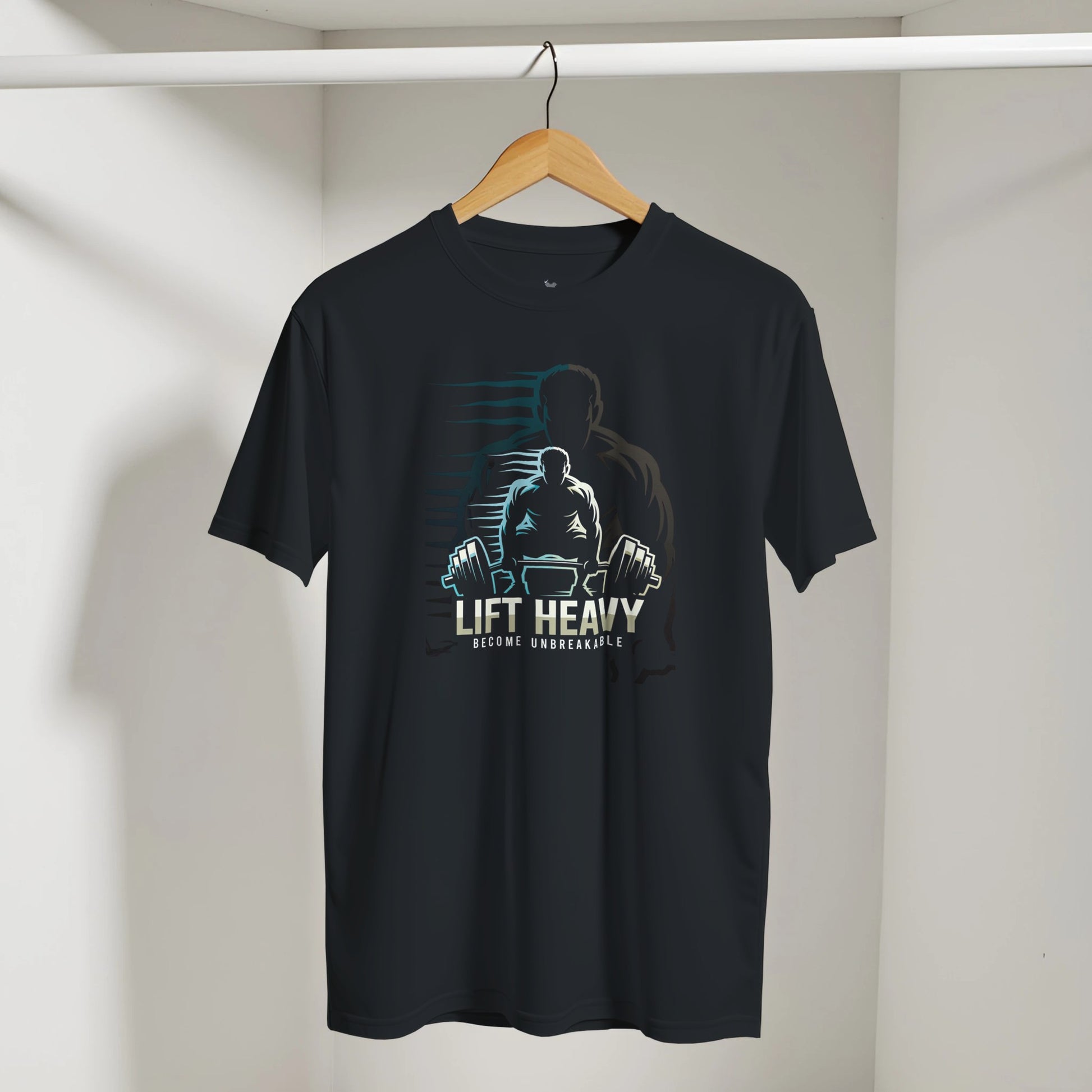 Black t-shirt with a graphic design of a person lifting weights and text 'Lift Heavy Become Unbreakable' on a hanger against a white wall.