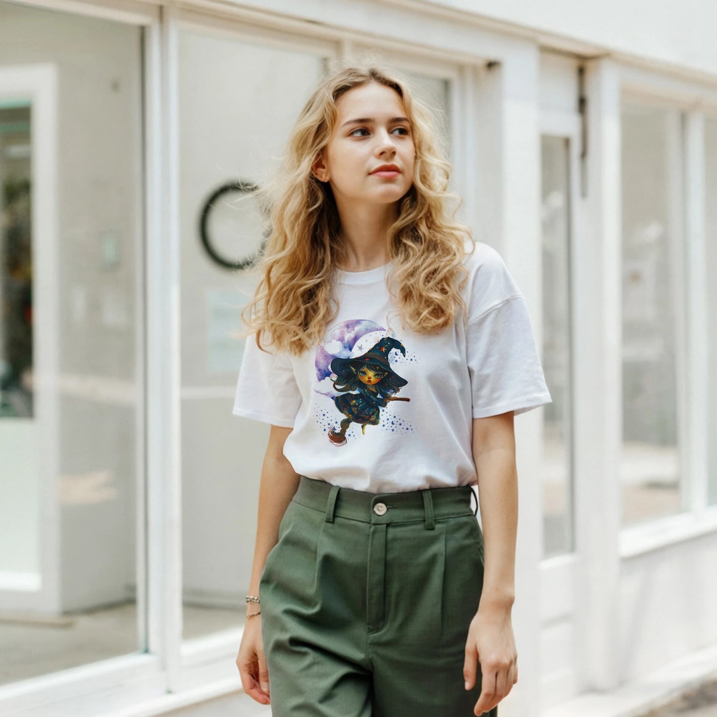 Woman wearing a white t-shirt with a graphic design and green pants in an indoor setting.