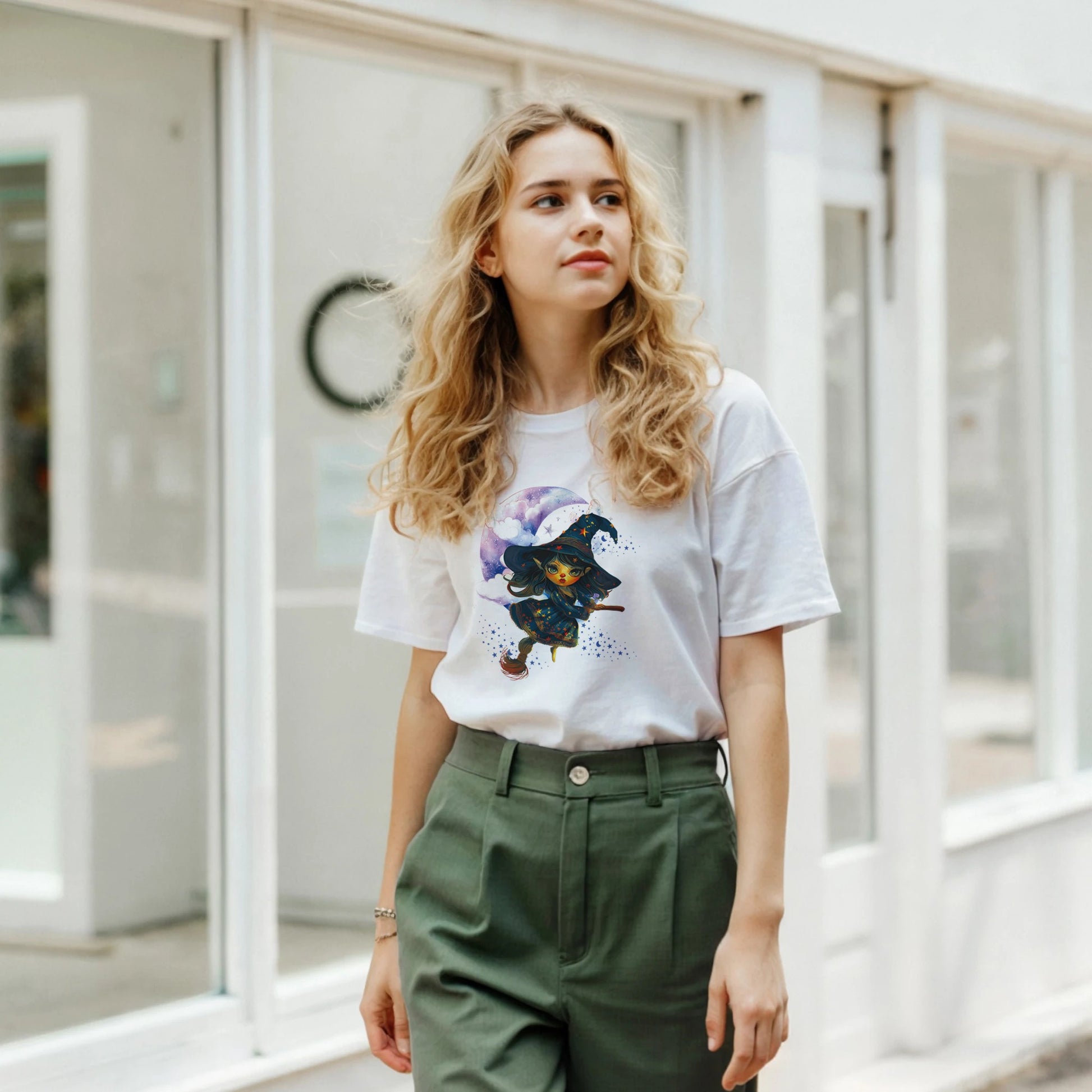 Woman wearing a white t-shirt with a graphic design and green pants in an indoor setting.