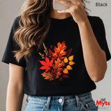 Person wearing a black t-shirt with autumn leaf design, holding a phone.