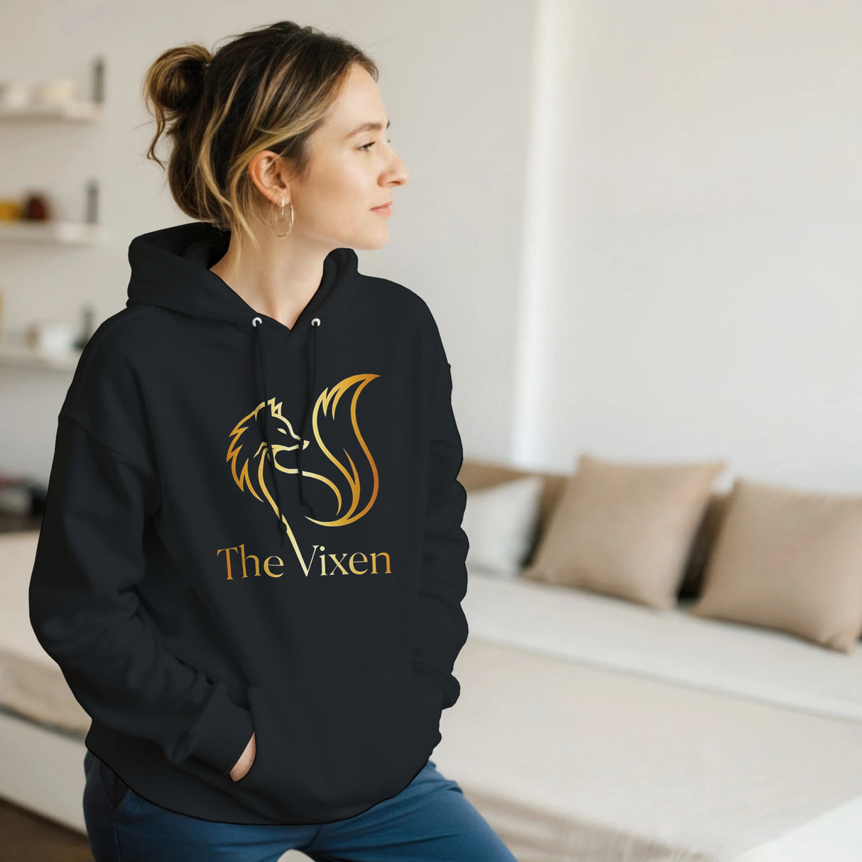 Person wearing a black hoodie with Gold fox vixen design in a room.