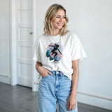 Woman wearing a white t-shirt with a graphic design and blue jeans indoors.