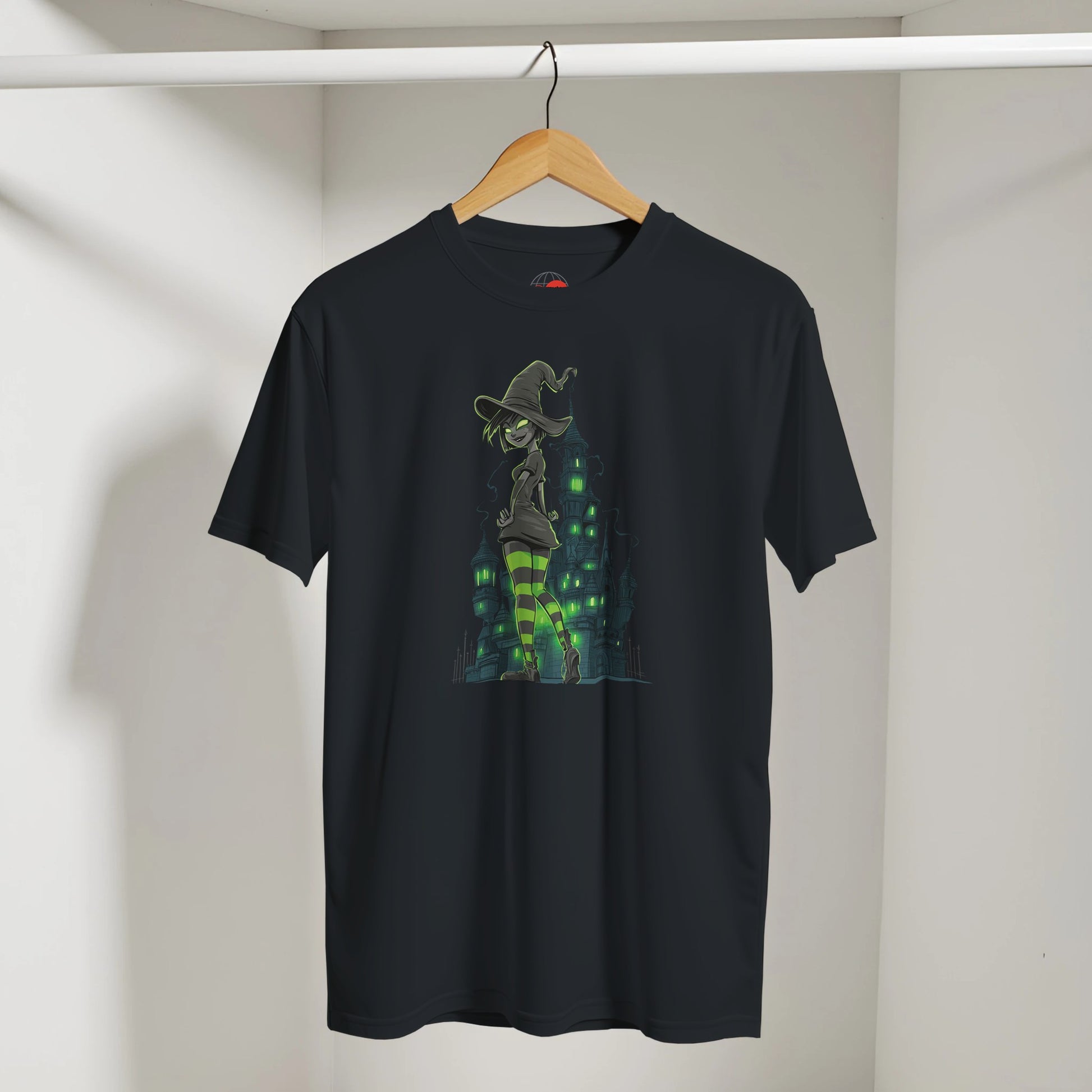 Black t-shirt with a graphic design of a witch on a broomstick hanging on a wooden hanger against a white wall.
