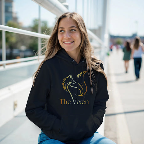Woman wearing a black hoodie with a graphic design and text, sitting outdoors.