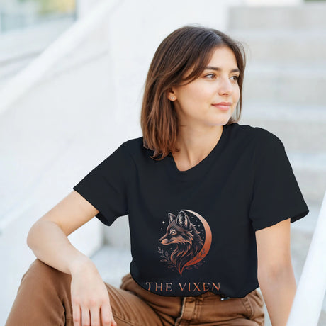 Woman wearing a black The Vixen Moon fox graphic T-shirt featuring a detailed celestial fox portrait, crescent moon, stars and botanical artwork.