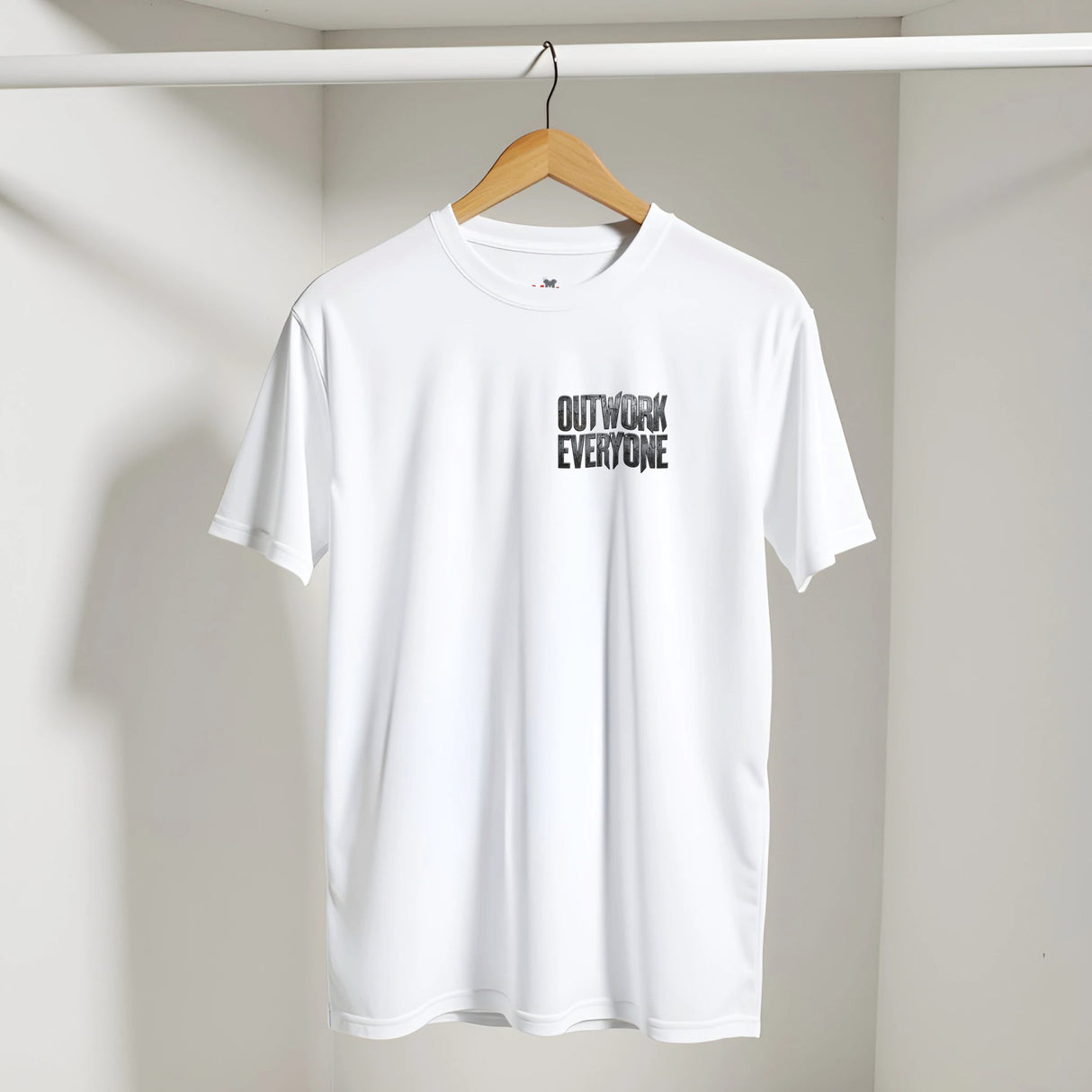 White t-shirt with 'OUTWORK EVERYONE' text on a hanger against a plain background