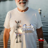 Older man wearing white Fitness Level Still Trying funny donkey graphic T-shirt beside the water.