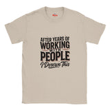 A Natural crewneck t-shirt with a humorous graphic that reads 'AFTER YEARS OF WORKING WITH PEOPLE I Deserve This' in black and white text, displayed on a clean white background.