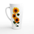 A tall white ceramic latte mug featuring a graphic print of three yellow sunflowers with dark brown centers and green leaves, shown against a plain white background.