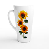 A tall white ceramic latte mug featuring a graphic print of three yellow sunflowers with dark brown centers and green leaves, shown against a plain white background.