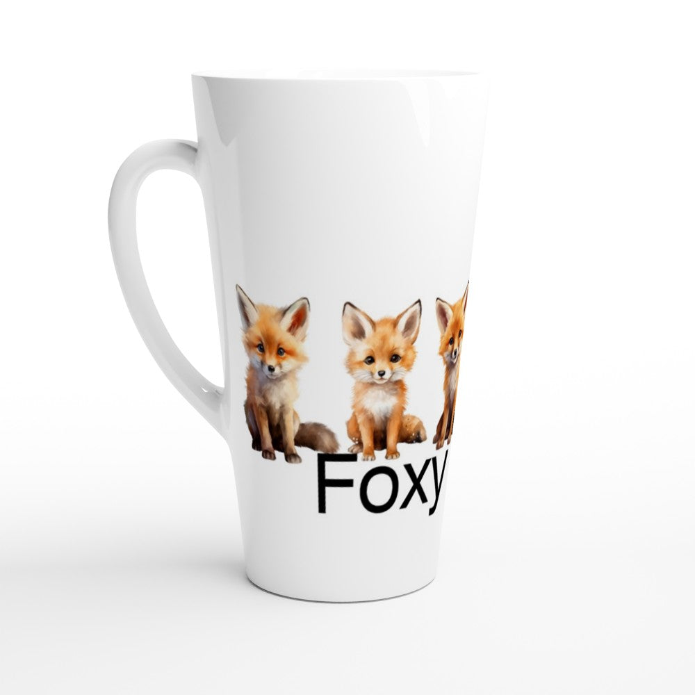 A white ceramic latte mug featuring three cute orange-red fox illustrations and the partial text 'Foxy' printed on the front, set against a clean white background.