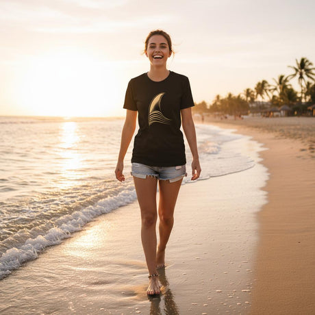 Woman walking on a beach at sunset wearing a black t-shirt with a logo.