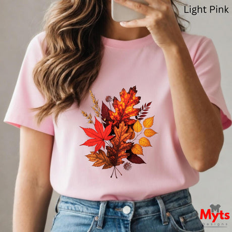 Person wearing a pink t-shirt with autumn leaf design, holding a phone.