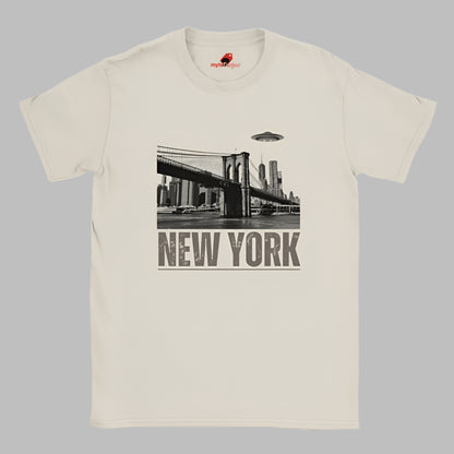 Sand colored soft casual tee showing the New York City skyline with a stylized spaceship graphic soaring above, printed on ultra-soft Gildan 64000 cotton.