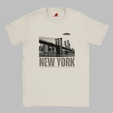 Sand colored soft casual tee showing the New York City skyline with a stylized spaceship graphic soaring above, printed on ultra-soft Gildan 64000 cotton.