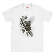 A white short-sleeve crewneck t-shirt featuring a watercolor-style graphic of a koala sitting on a tree branch with eucalyptus leaves. The brand name 'The Myts' is printed in red on the inside neck label.