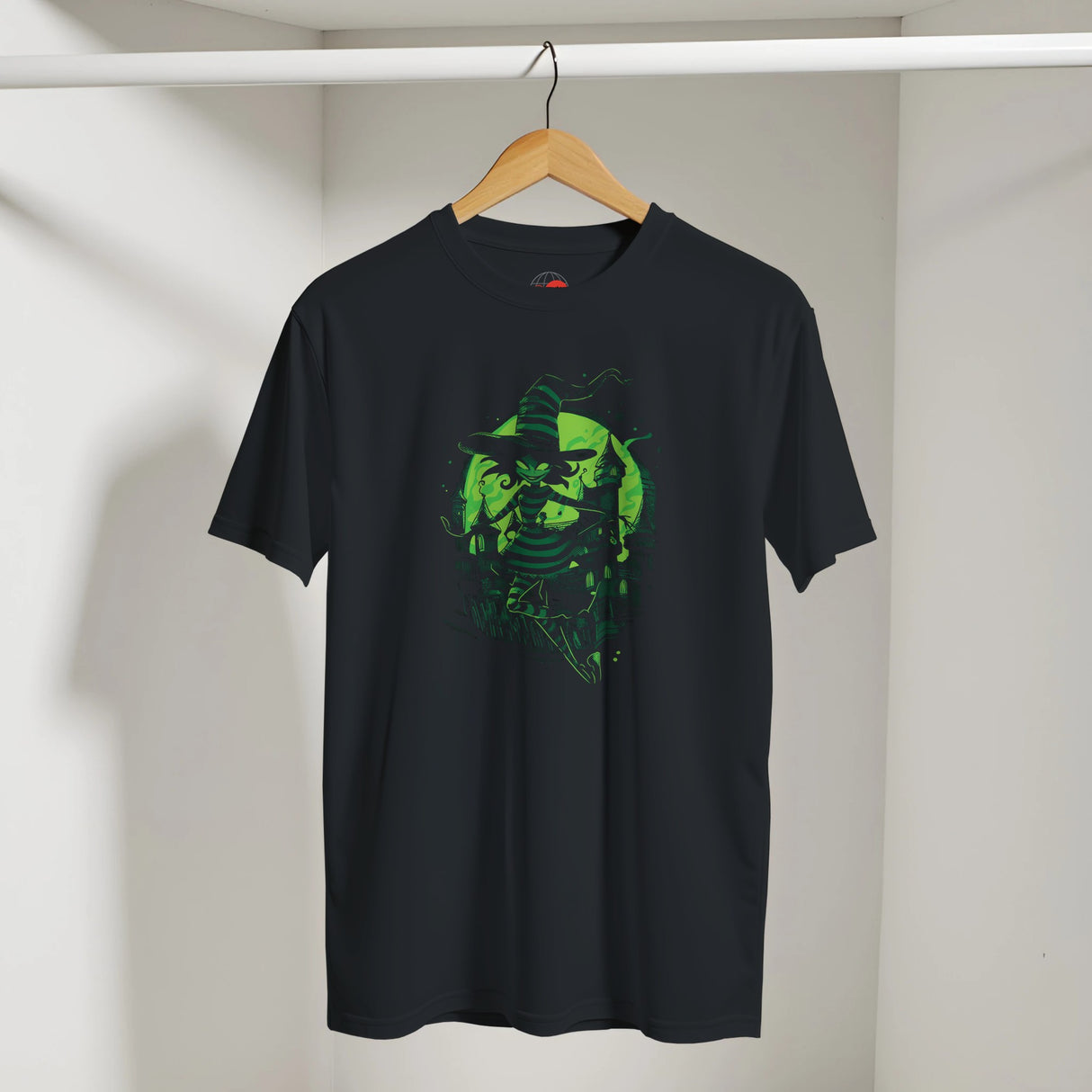 Black t-shirt with green graphic design on a hanger against a white wall