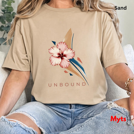 Close-up of a woman wearing a Sand UNBOUND hibiscus graphic T-shirt with distressed blue jeans.